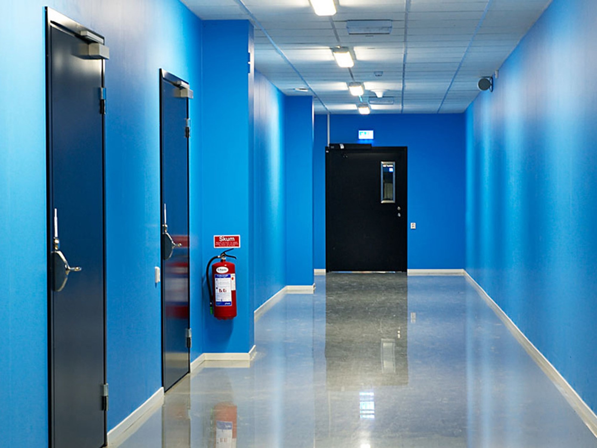 Svarta ståldörrar i blå korridor