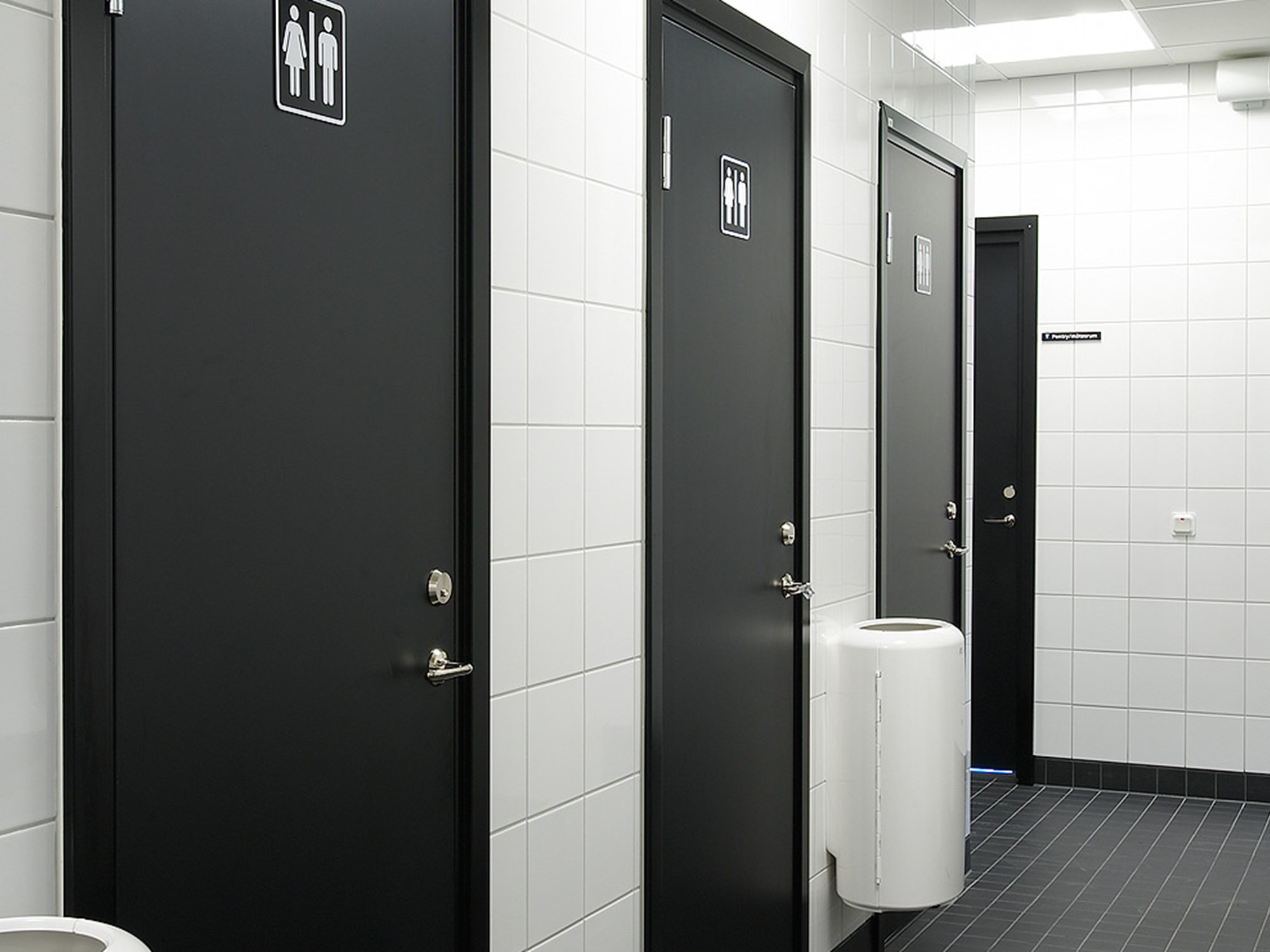 Svarta våtrumsdörrar i offentligt badrum