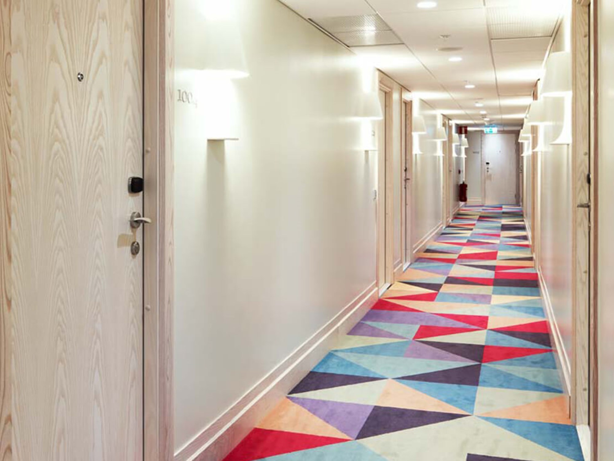 Hotellkorridor med färgglad matta och rumsdörrar